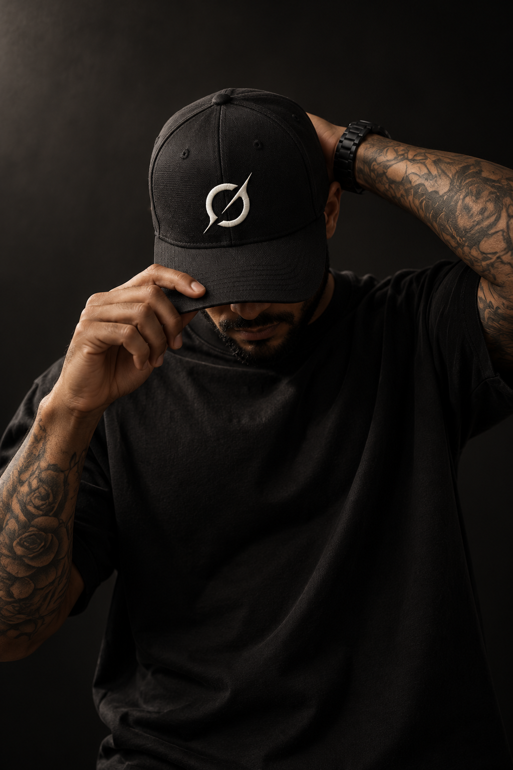 Male model wearing a black JGT baseball cap with off-white front embroidery and a minimalist black streetwear outfit.